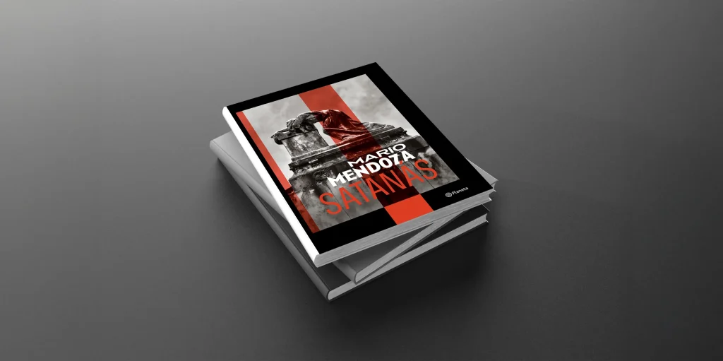Libro "Satanás" de Mario Mendoza, con tapa negra, roja y estatua oscura, sobre otros libros.